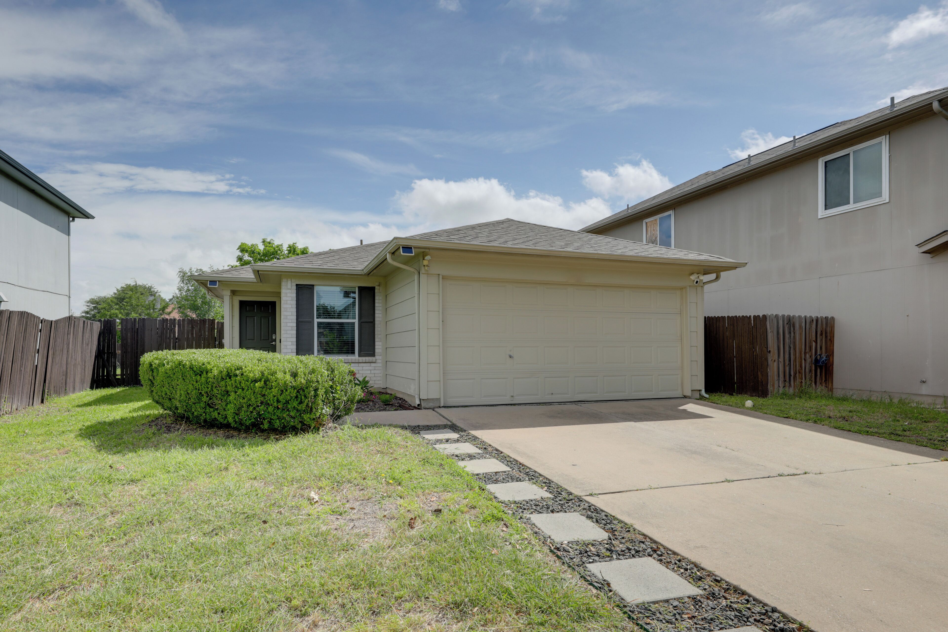 A residential house with a garage, a lawn, and a wooden fence.