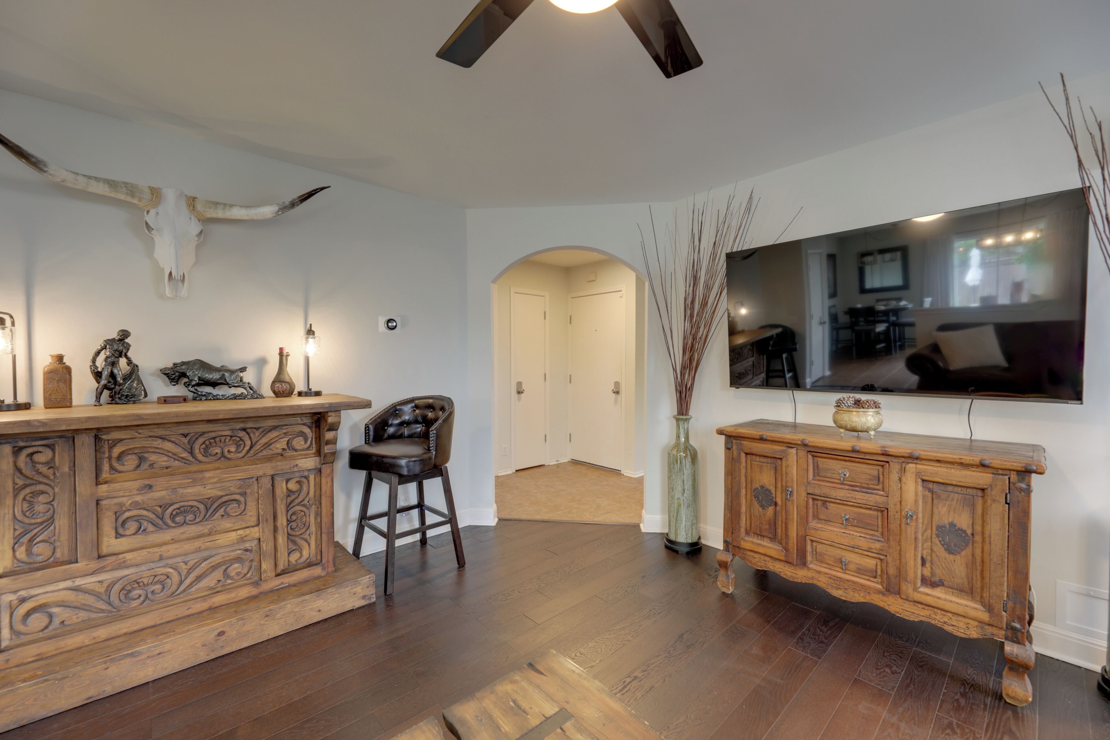 A room with a wooden bar, a large mirror, and a bull skull on the wall.