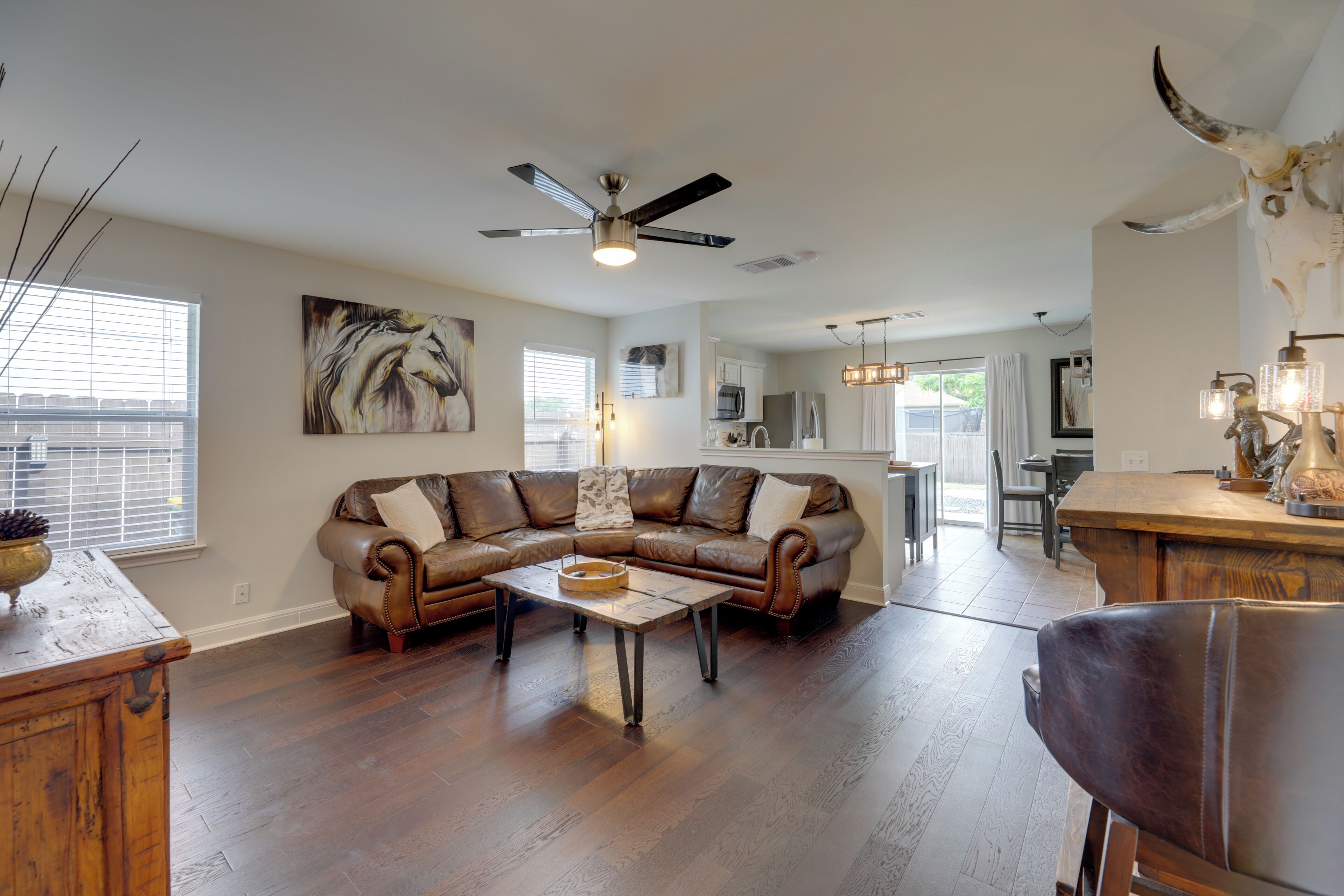A spacious living room with a leather sectional sofa, a wooden coffee table, and a ceiling fan.