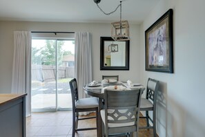 A dining area with a round table, four chairs, a chandelier, a large mirror, and a framed picture on the wall. - Private Yard & Deck! Group-friendly Haven in Manor (Manor)