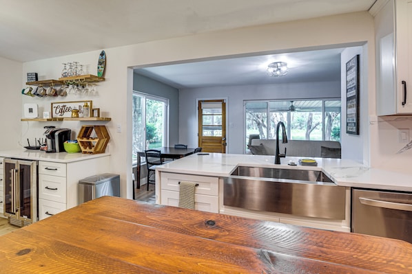 A modern kitchen with a wooden dining table, stainless steel appliances, and a view of the outdoors.