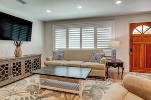 A living room with a sofa, a coffee table, a cabinet, a television, and a door.