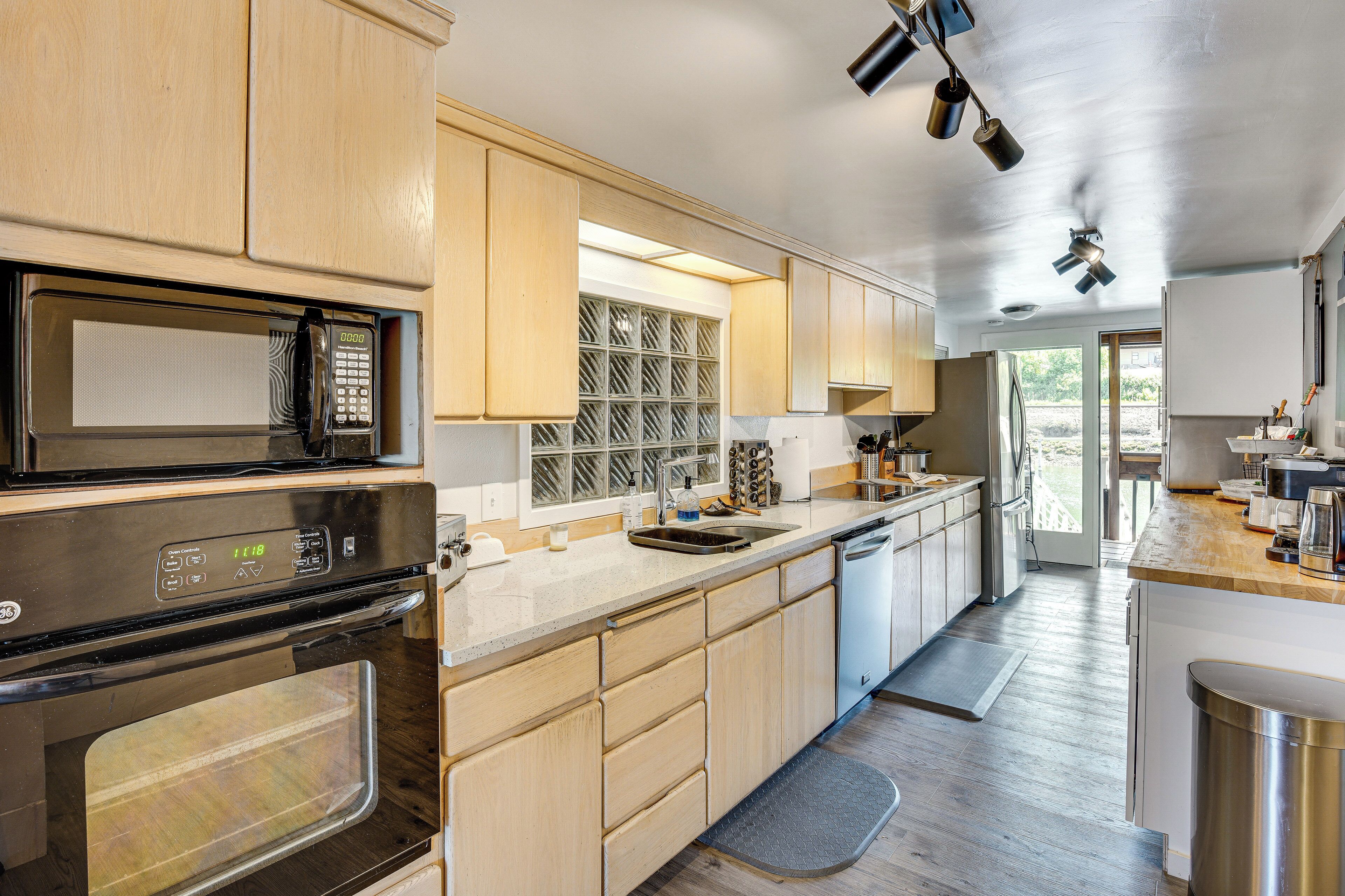 A modern kitchen with stainless steel appliances, wooden cabinets, and a view to the outside.