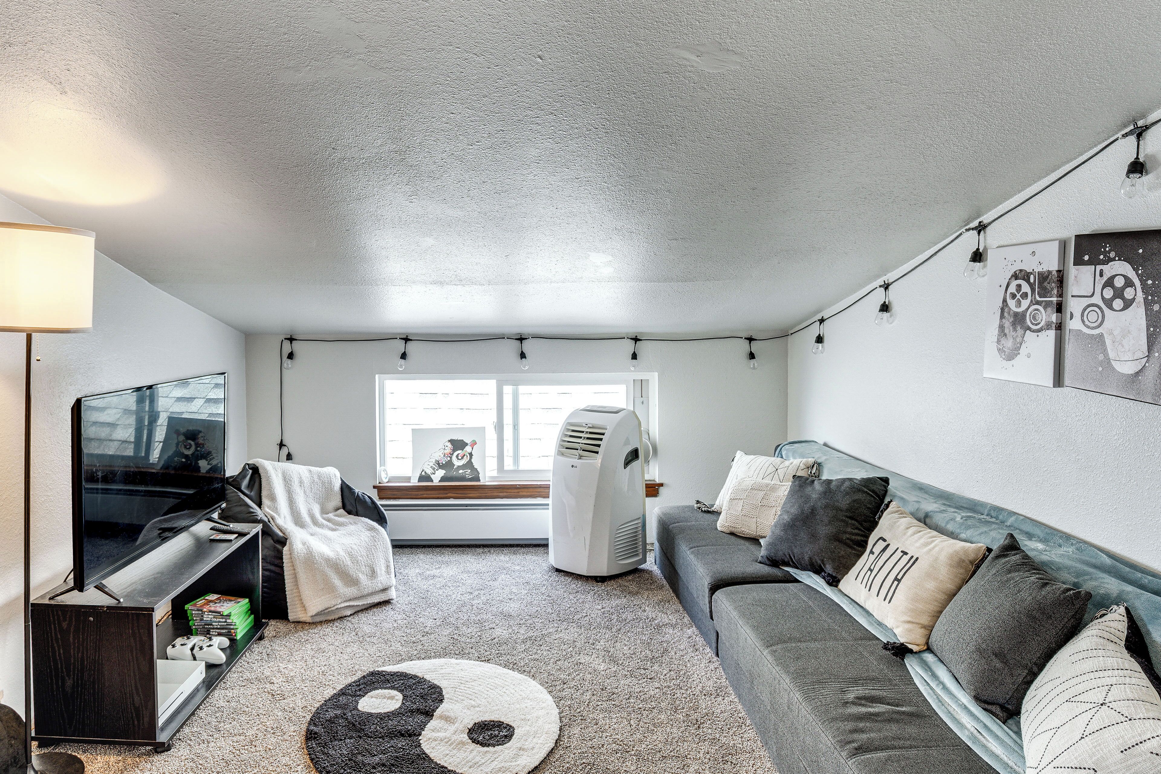 A living room with a TV, gaming console, and a couch with decorative pillows.