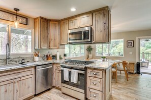 A kitchen with wooden cabinets, a stainless steel stove, and a built-in microwave. - Pool & Dual Decks! Modern Trinity River Retreat (Douglas City)