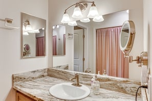 A bathroom with a marble sink, a large mirror, and a light fixture above the mirror. - Pool & Dual Decks! Modern Trinity River Retreat (Douglas City)
