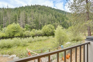 A view of a river with a forested hillside, a wooden deck, and a metal railing. - Pool & Dual Decks! Modern Trinity River Retreat (Douglas City)