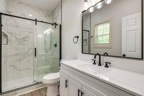Une salle de bain avec une douche Ă parois de verre, un lavabo blanc et un grand miroir.