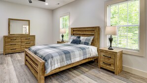 Ein Schlafzimmer mit einem Bett, Nachttischen aus Holz, einem Deckenventilator und einem Fenster mit Jalousien.