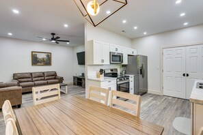 Une cuisine moderne avec des meubles blancs, un four à micro-ondes, un réfrigérateur et un coin repas comprenant une table et des chaises en bois.