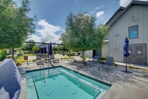A swimming pool with lounge chairs and umbrellas, surrounded by trees and a building. - Premium Ontario Home w/ Resort-style Perks! (Ontario)
