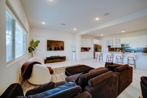 A spacious living area with a large sofa set, a flat-screen TV, and a kitchen in the background. - Premium Ontario Home w/ Resort-style Perks! (Ontario)