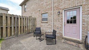 Un bâtiment en briques avec une clôture en bois, une porte et deux chaises.