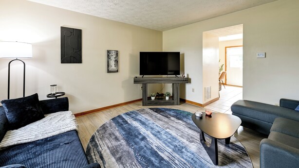 Un salon avec un canapé, une table basse, un téléviseur posé sur un meuble et un tapis à motifs.