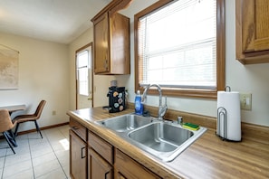 A kitchen with wooden cabinets, a double sink, a window with blinds, and a coffee maker. - Great for Families! Richmond Townhome w/ Patio (Richmond)