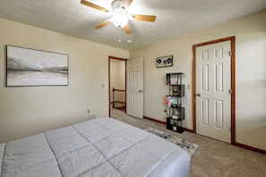 A bedroom with a bed, a ceiling fan, a door, a staircase, and a wall-mounted shelf. - Great for Families! Richmond Townhome w/ Patio (Richmond)