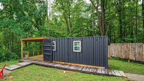 A compact, dark-colored cabin with a wooden deck and a small window. - Tiny Cabin Nature Retreat Near Blue Rock (Cumberland)