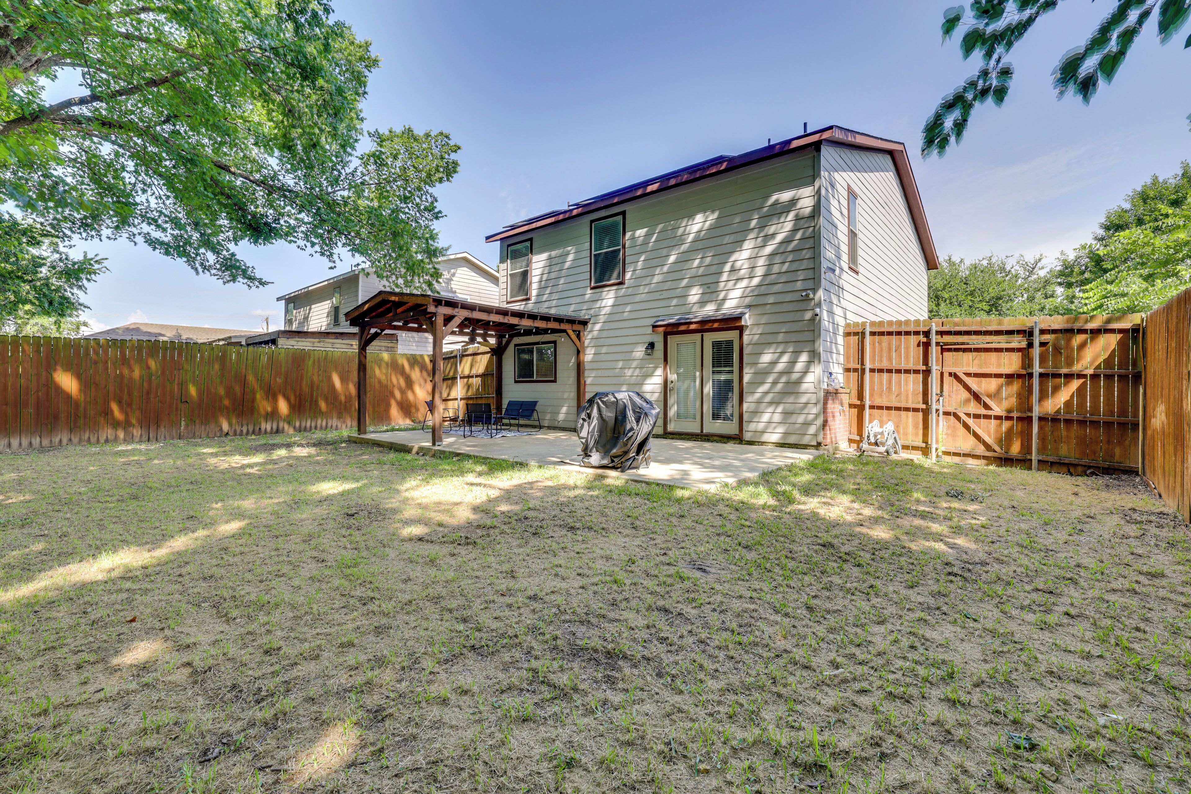 A house with a covered patio, a fenced yard, and a garage.