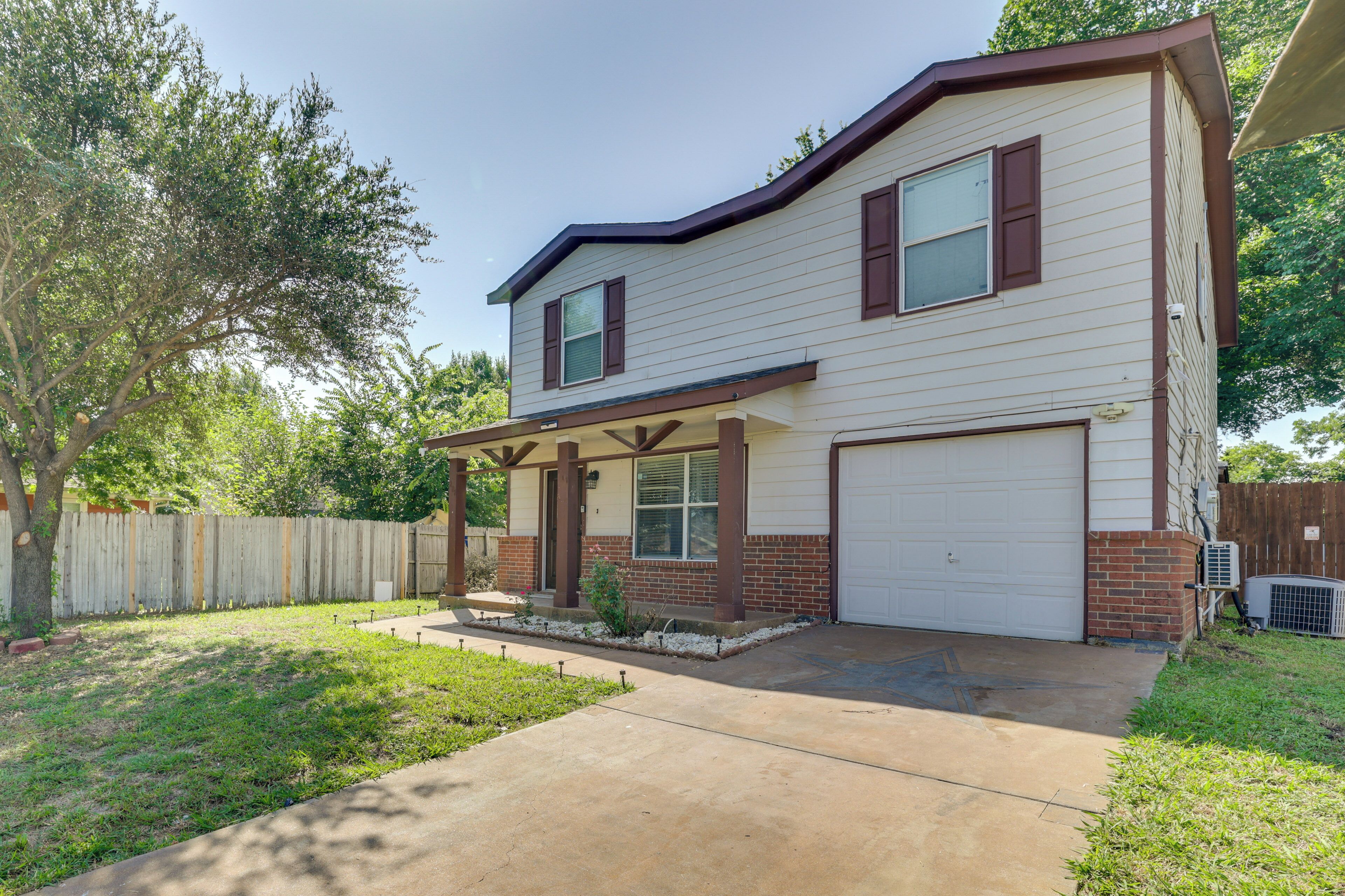 A two-story house with a garage, a covered porch, and a fenced backyard.