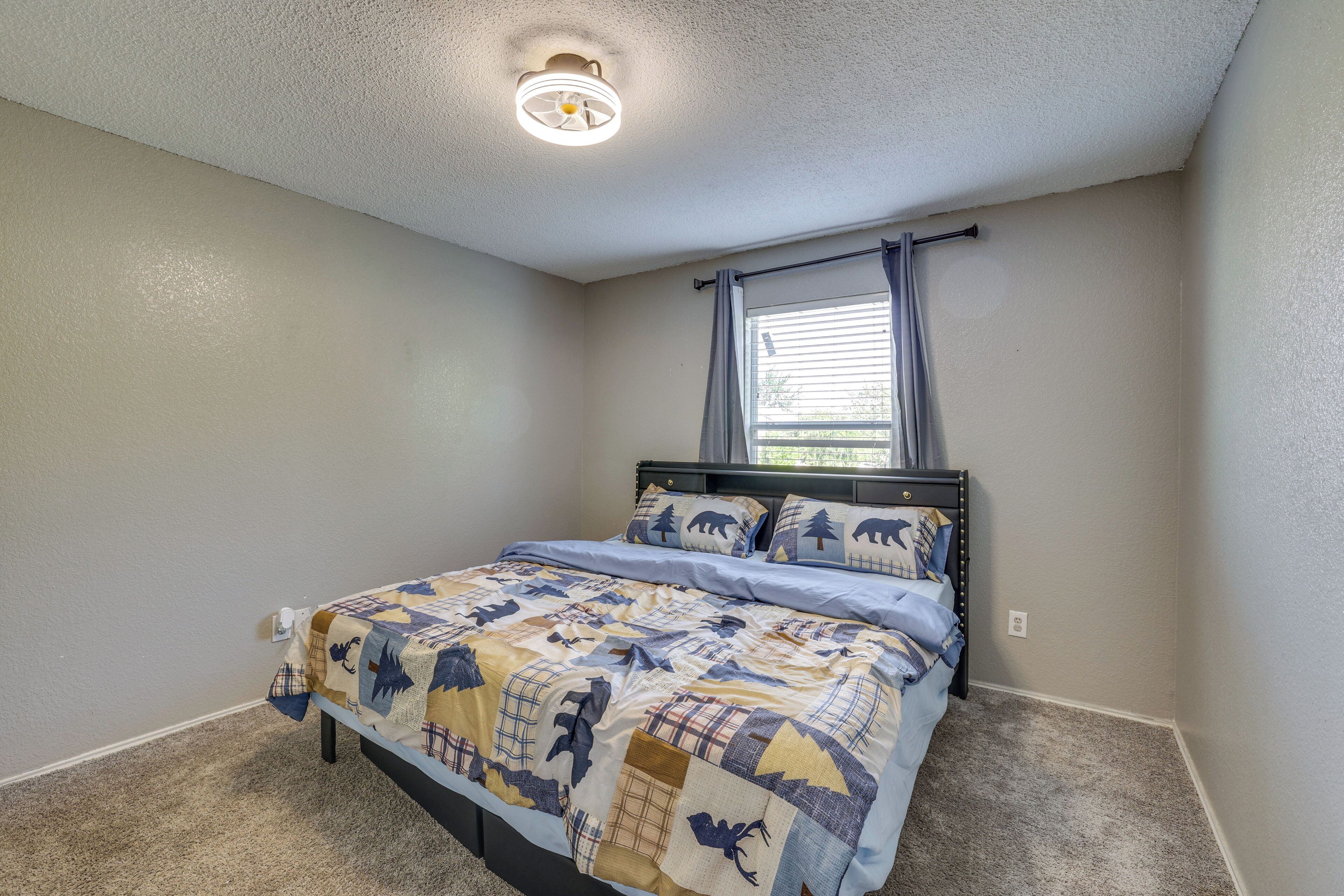 Een slaapkamer met een bed, een raam met gordijnen, een plafondlamp en een vloerbedekking.
