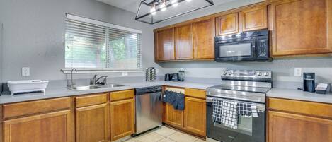 A kitchen with wooden cabinets, a dishwasher, a microwave, and a stove.