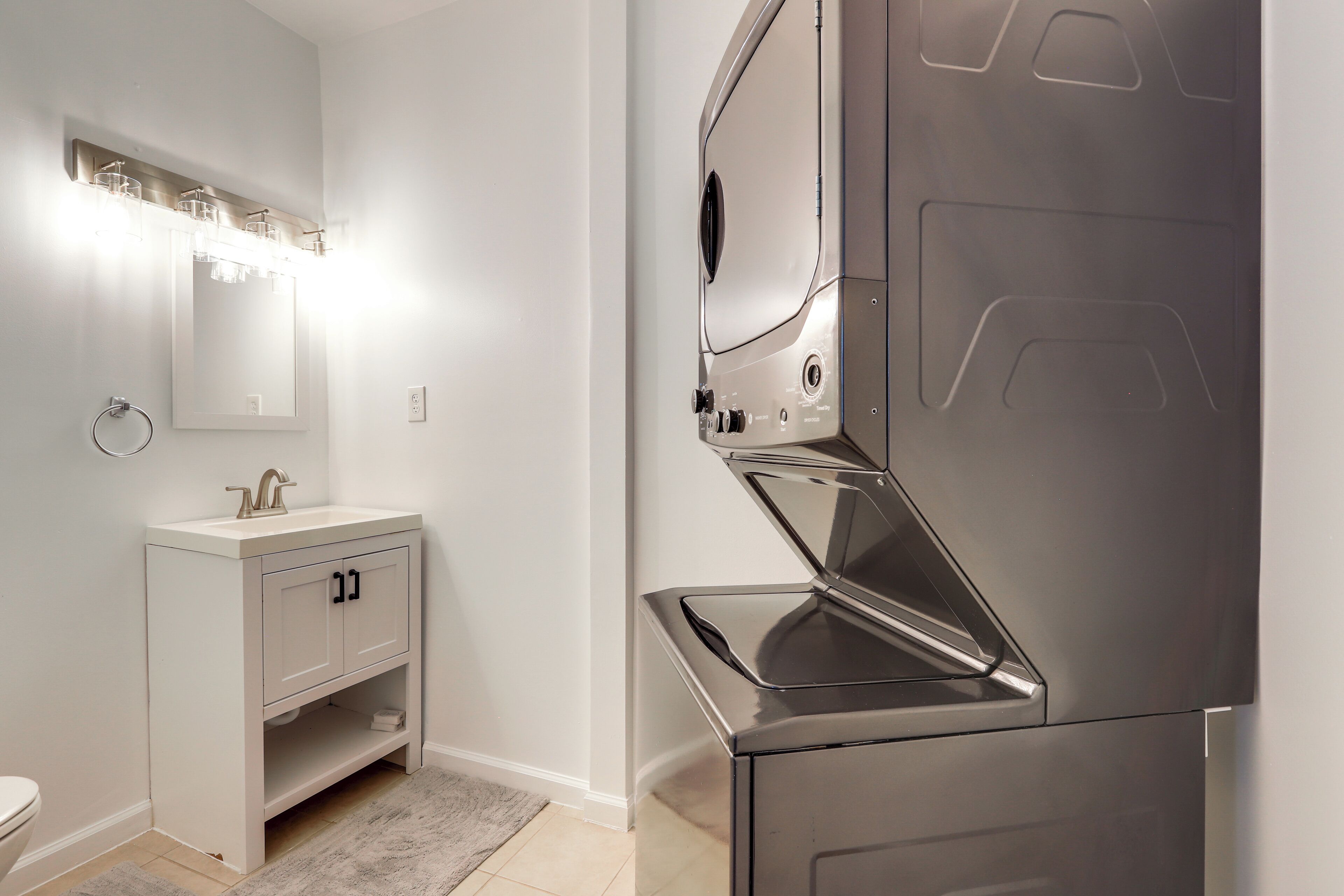Une salle de bain moderne équipée d’un meuble-lavabo, d’un miroir et d’un lave-linge encastré.