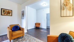Ein modernes Wohnzimmer mit einem braunen Ledersofa, einem gemusterten Teppich und einem blauen Kissen.