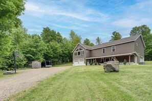 A two-story house with a large garage, a covered porch, and a well-maintained lawn.