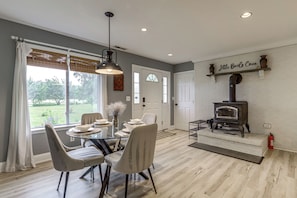 A dining area with a glass table, chairs, and a hanging light fixture.