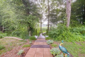 A pathway leading through a lush garden with a peacock.