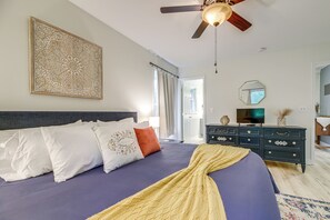 Une chambre à coucher avec un lit, un ventilateur de plafond, une télévision et une commode.