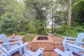 An outdoor seating area with Adirondack chairs, a fire pit, and a garden path.