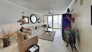 A spacious living room with a sofa, coffee table, and decorative items. - The Pearl of Navarre #1502 | Gulf Front + Resort Amenities (Navarre Beach)