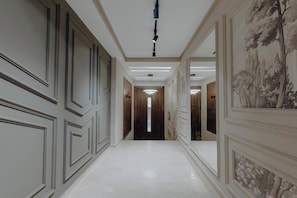 A hallway with a polished floor, decorative moldings, and a modern light fixture. - The Shelter (Casablanca)