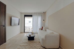 Una sala de estar moderna con un sofá, una mesa de centro y un televisor montado en la pared.