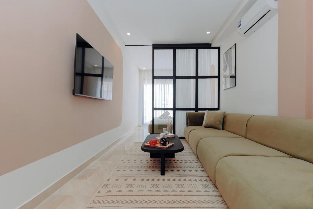 A modern living room with a sofa, a coffee table, and a TV mounted on the wall.