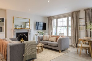A living room with a fireplace, sofa, TV, and dining area. - Stunning Notting Hill Flat (London)
