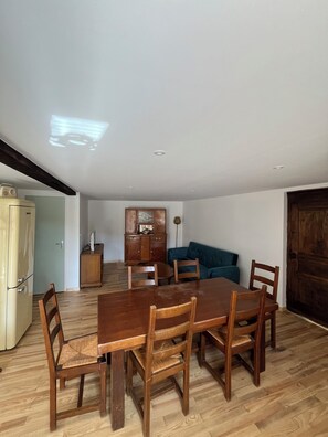 Ein Essbereich mit Holztisch und -stühlen, einem blauen Sofa und einem Holzschrank.