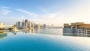 Une piscine à débordement située sur le toit, offrant une vue panoramique sur la ville, avec ses gratte-ciel et sa grande roue.