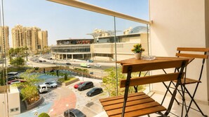 Un balcon donnant sur un parking, des immeubles et un rond-point.