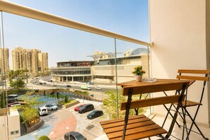 A balcony with a view of a parking lot, buildings, and a roundabout. - Rentico | Infinity Pool Studio on Palm Jumeirah (Dubai)