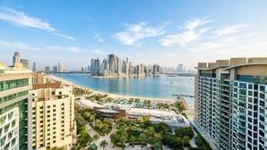Un grand hôtel, situé dans un immeuble de grande hauteur, qui offre une vue sur une plage et dont l’arrière-plan est dominé par le profil de la ville.