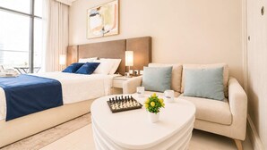 Une chambre d’hôtel avec un lit, un canapé, une table basse, un jeu d’échecs et un tableau au mur.