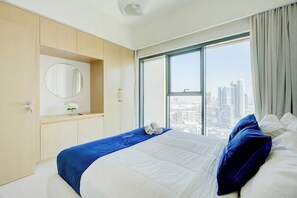 Ein Hotelzimmer mit einem großen Bett, Blick auf die Stadt, einem runden Spiegel und einem Fenster mit Vorhängen.