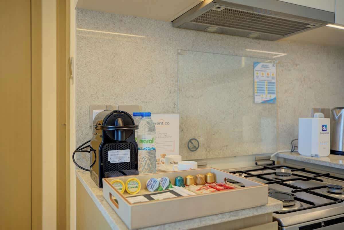 Una cocina con una cafetera, dispensador de agua y una caja de cápsulas de café.