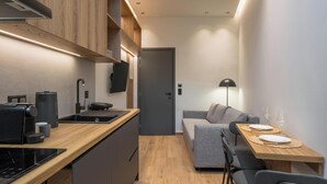 Eine kleine Wohnküche mit Holzausstattung, modernen Geräten und einem grauen Sofa.