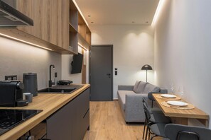Eine kleine Wohnküche mit Holzausstattung, modernen Geräten und einem grauen Sofa.