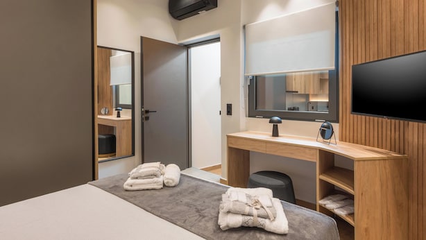 Ein modernes Hotelzimmer mit Bett, Schreibtisch, Fernseher und Spiegel.