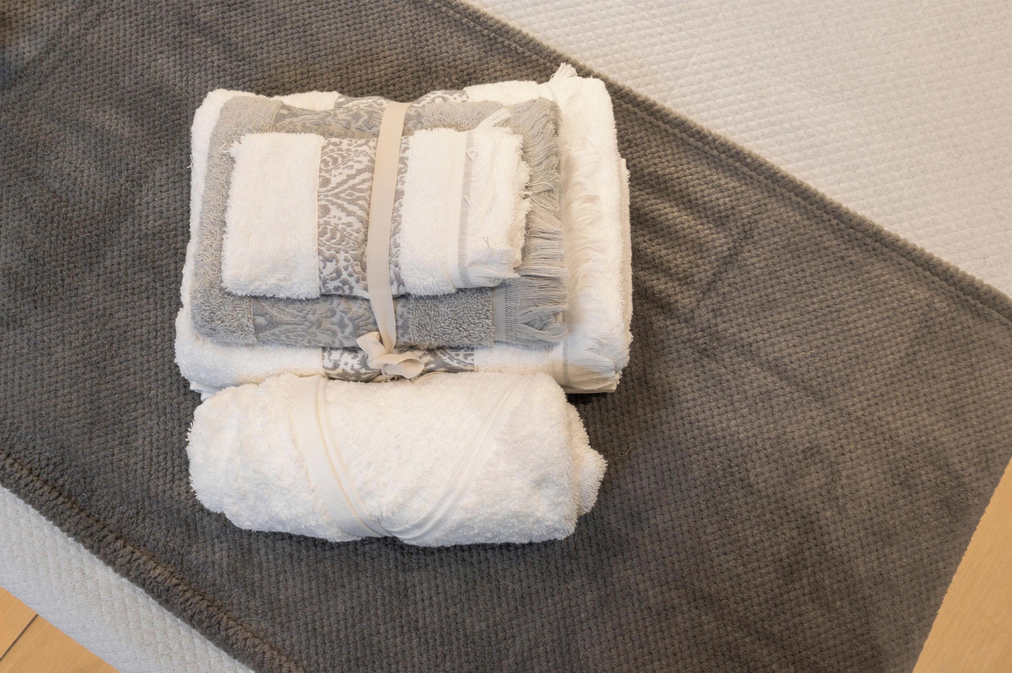 A neatly folded towel set on a textured gray mat.