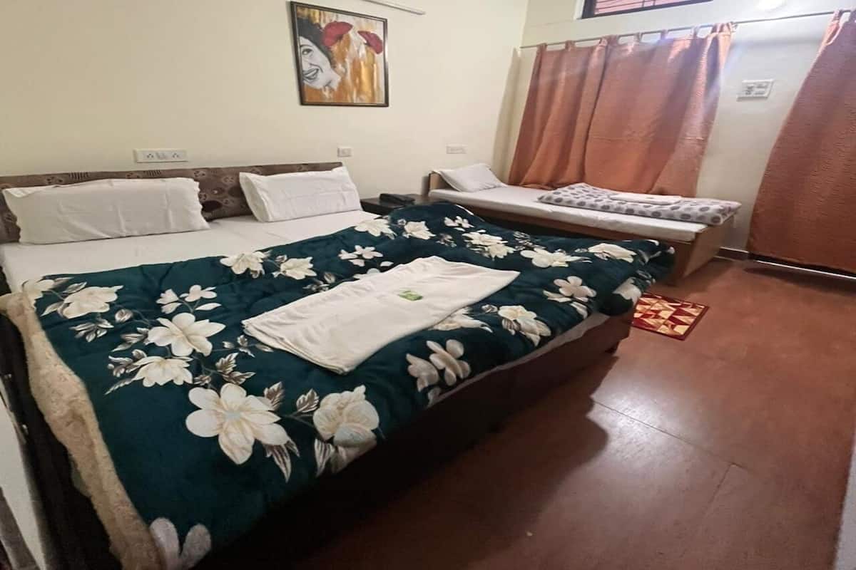 Un dormitorio con cama, mesita de noche, silla, ventana con cortinas y una obra de arte colgada en la pared.